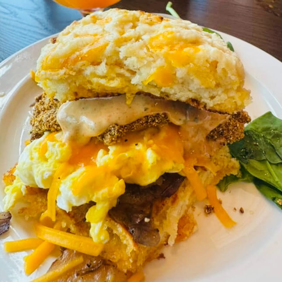 Eat My Biscuits' southern biscuit sandwich with fried chicken, gravy, eggs, cheese, and spinach.